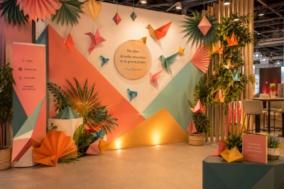 Vitrine de pâtisserie avec gâteaux décorés, tarte aux pommes, bûche et décorations florales sous un éclairage chaleureux.