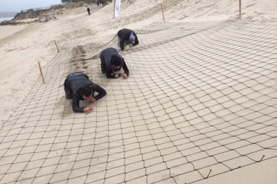 Groupe de personnes s'étirant sur une plage de sable face à la mer sous un ciel nuageux.