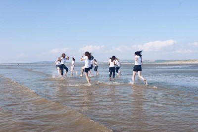 Groupe de personnes s'étirant sur une plage de sable face à la mer sous un ciel nuageux.