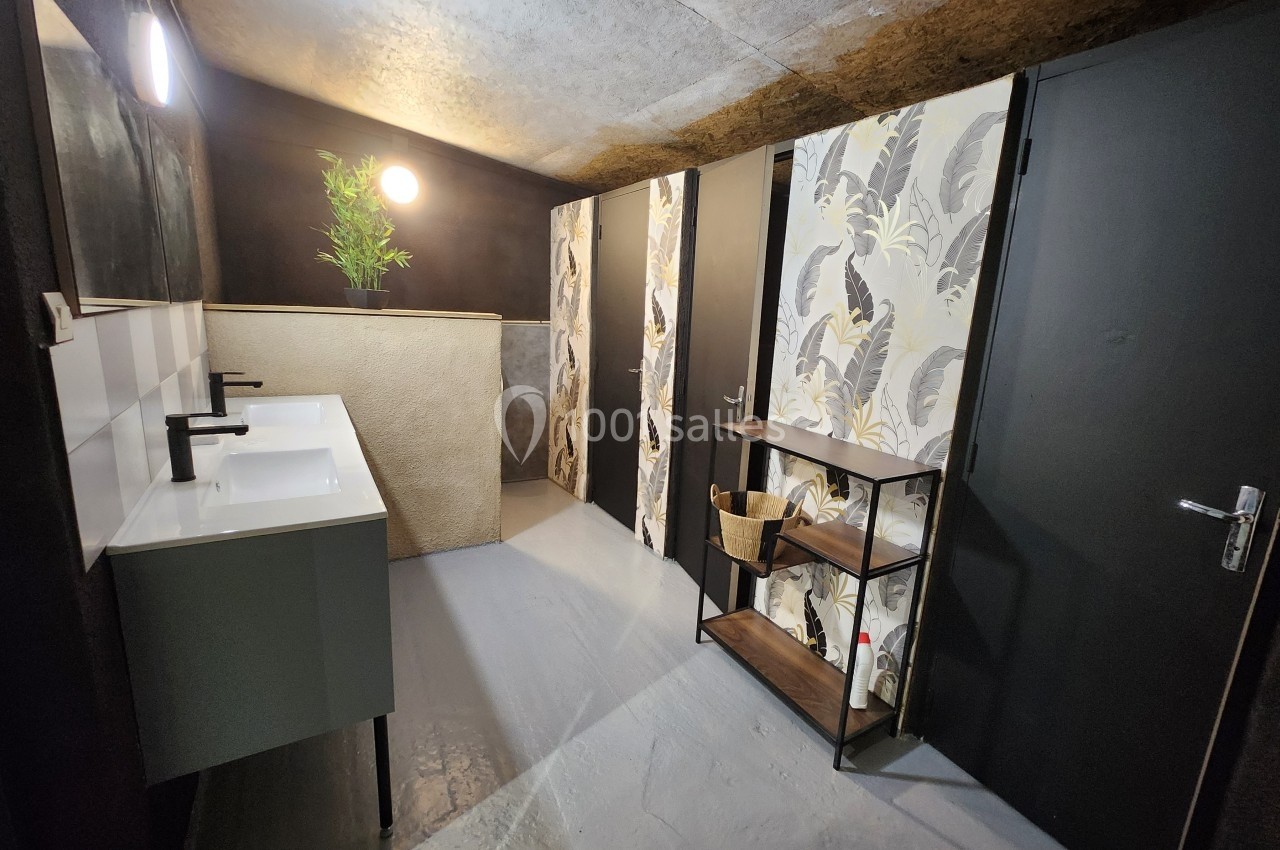 Salle de bain moderne avec deux lavabos, murs sombres, papier peint à motifs et étagère en bois.