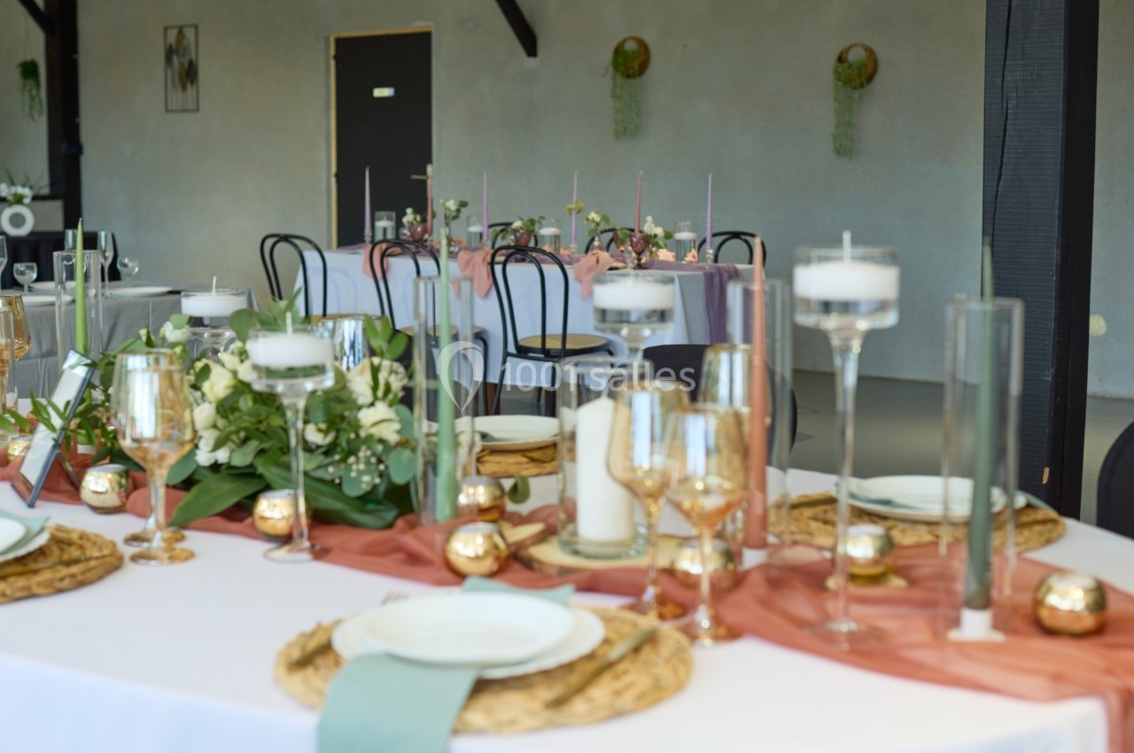 Table décorée pour un événement avec bougies, fleurs, nappes blanches et chemins de table en tissu rose.
