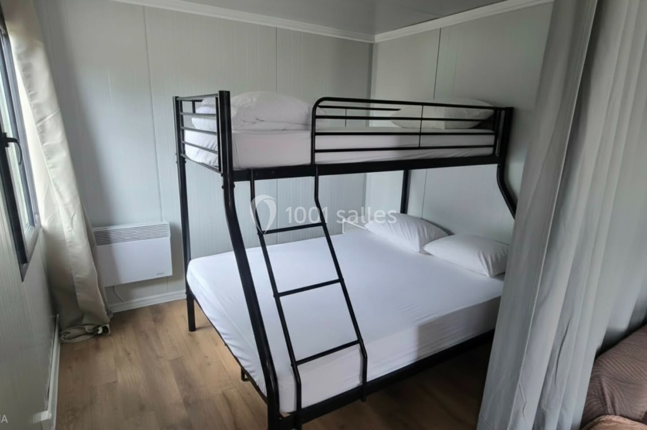 Lit superposé avec un lit simple en haut et un lit double en bas dans une chambre lumineuse avec parquet.