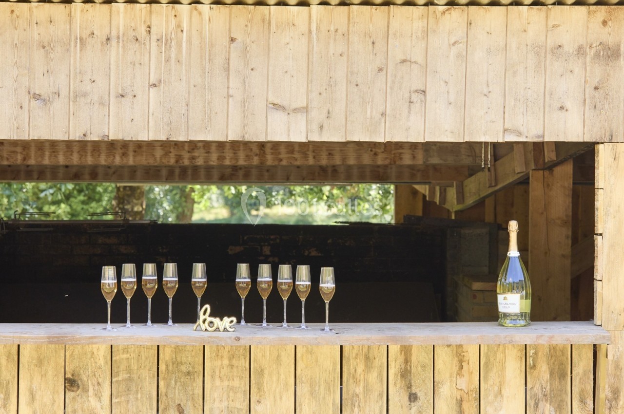 Huit flûtes de champagne alignées sur un comptoir en bois avec une bouteille et le mot ’love’ en décoration.