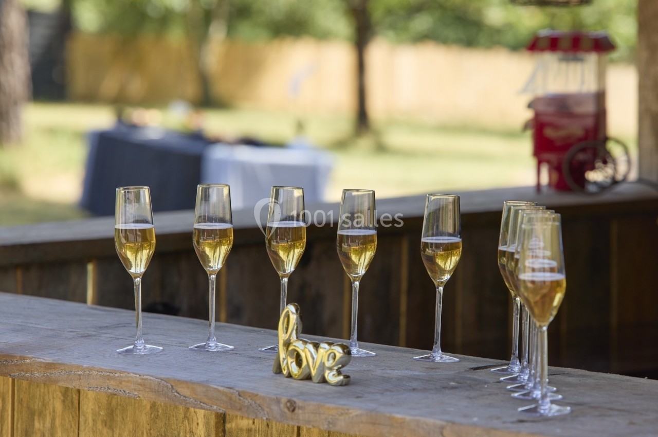 Huit flûtes de champagne alignées sur un comptoir en bois, avec une décoration dorée ’love’ au premier plan.