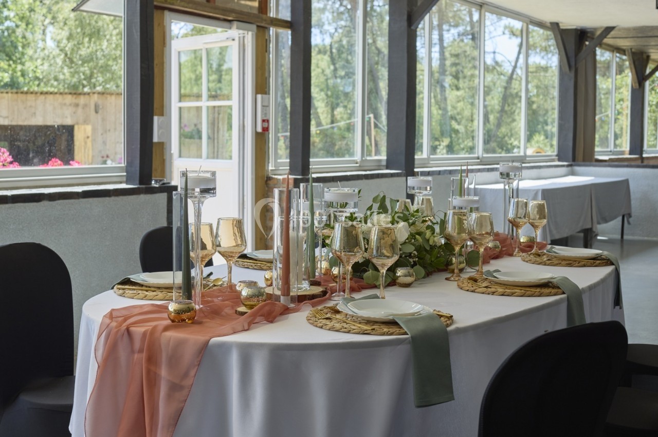 Table élégamment dressée avec nappes blanches, chemins de table colorés, bougies et vaisselle raffinée dans une salle…
