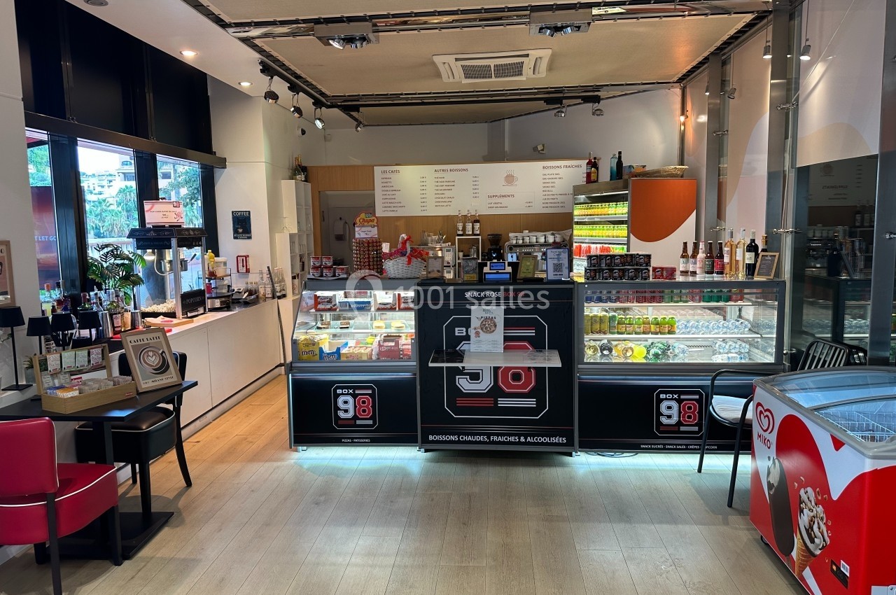 Intérieur d'une boutique avec comptoirs de vente proposant des snacks, boissons et glaces, éclairage moderne.
