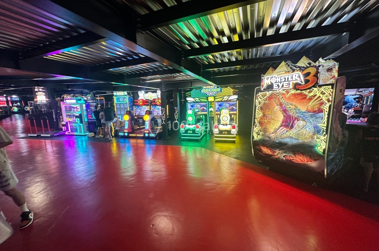 Salle d'arcade avec plusieurs machines de jeux lumineuses, dont une dédiée au jeu ’Monster Eye 3’.