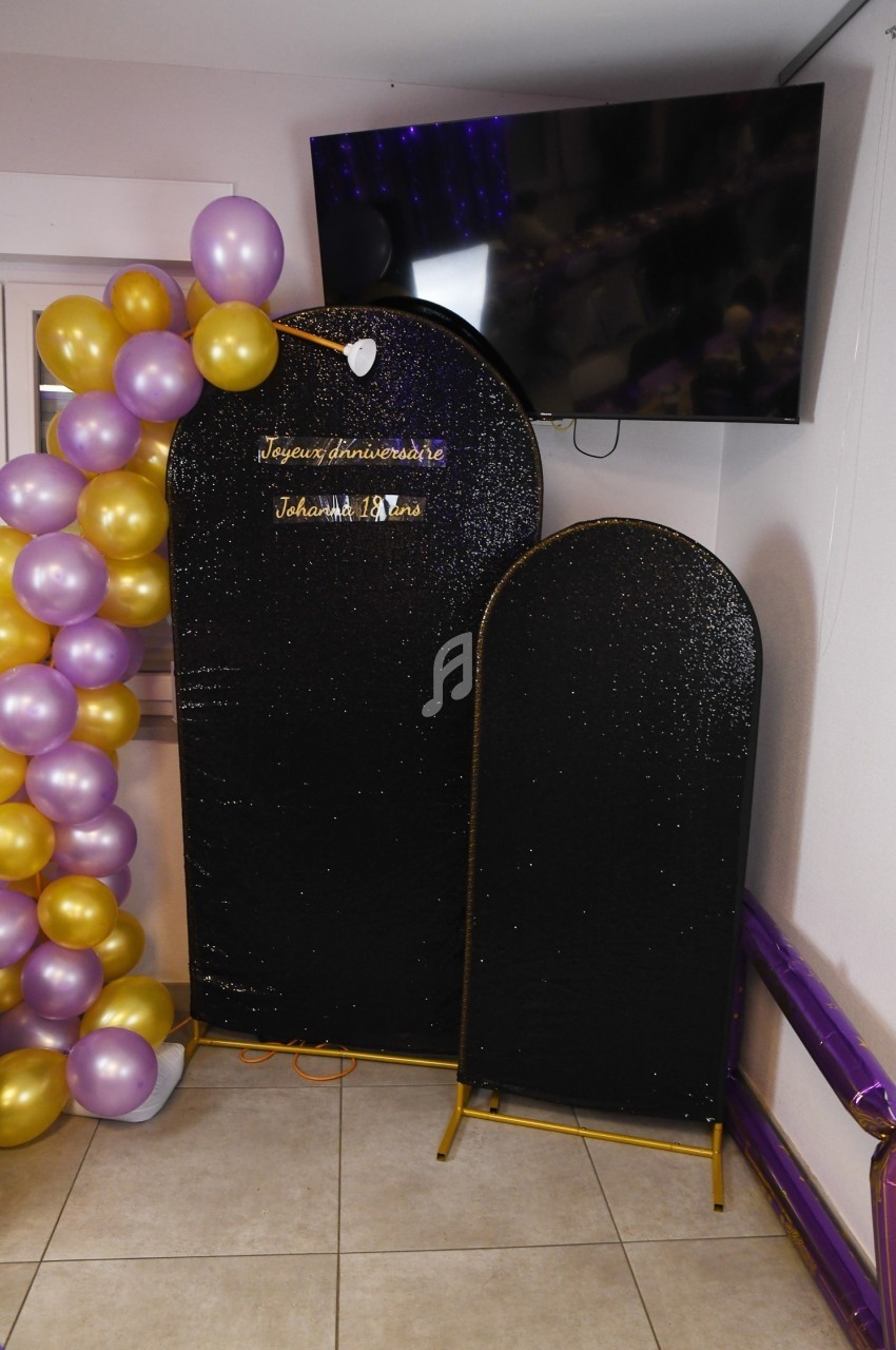 Mur décoratif noir pailleté avec ballon dorés et violets, et inscription ’Joyeux anniversaire Johann 18 ans’.