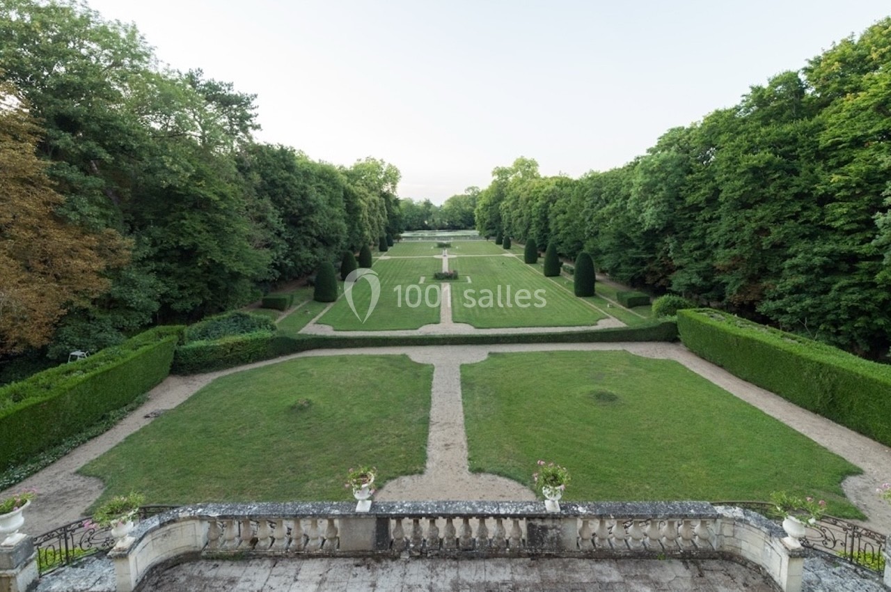 Vue d'un jardin à la française avec pelouses, allées gravillonnées, haies taillées et une fontaine centrale.