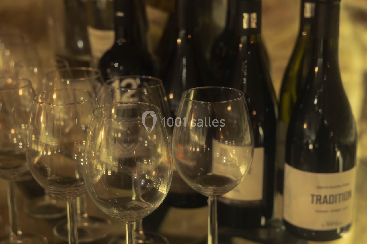 Bouteilles de vin rouge et verres à pied vides alignés sur une table en verre.