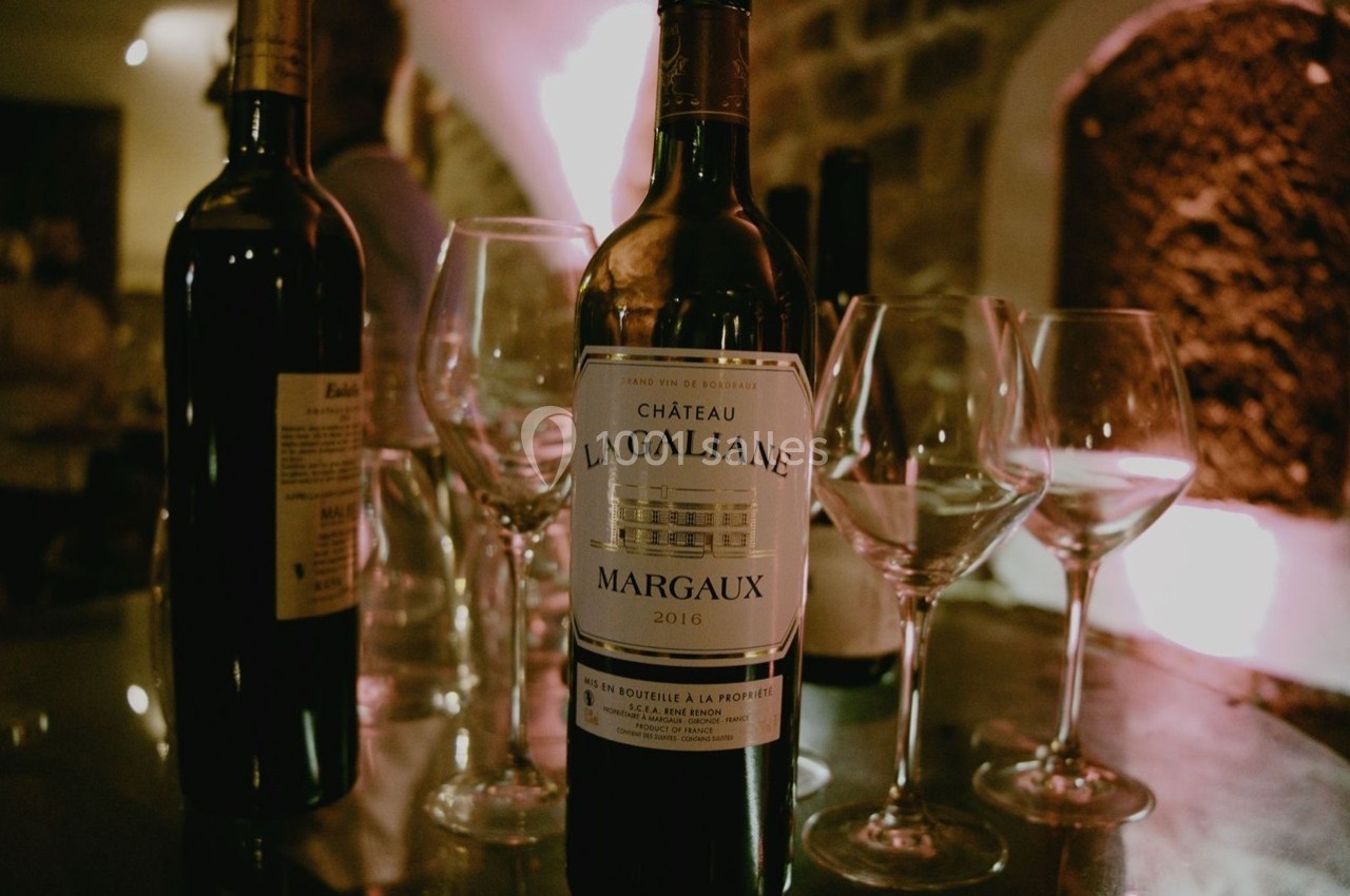 Bouteille de vin Château La Galiane Margaux 2016 entourée de verres à vin sur une table éclairée.