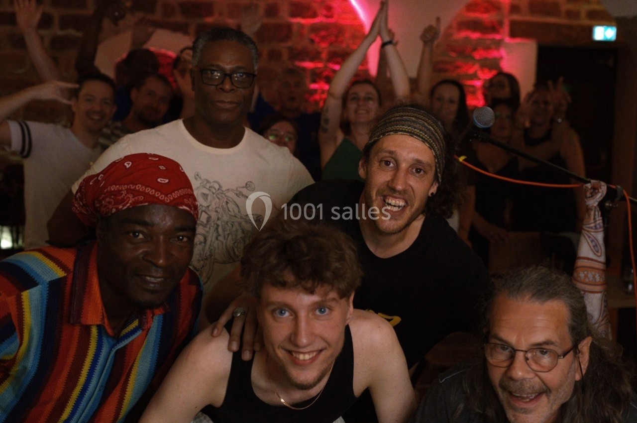 Un groupe de personnes souriantes posant dans une ambiance festive avec un éclairage rouge et des murs en pierre.