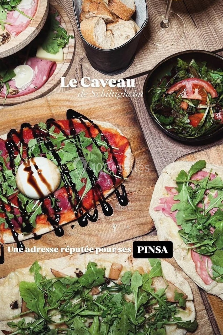 Plateau de pinsas garnies de roquette, burrata et charcuterie, accompagné de salade, pain et verre de vin.