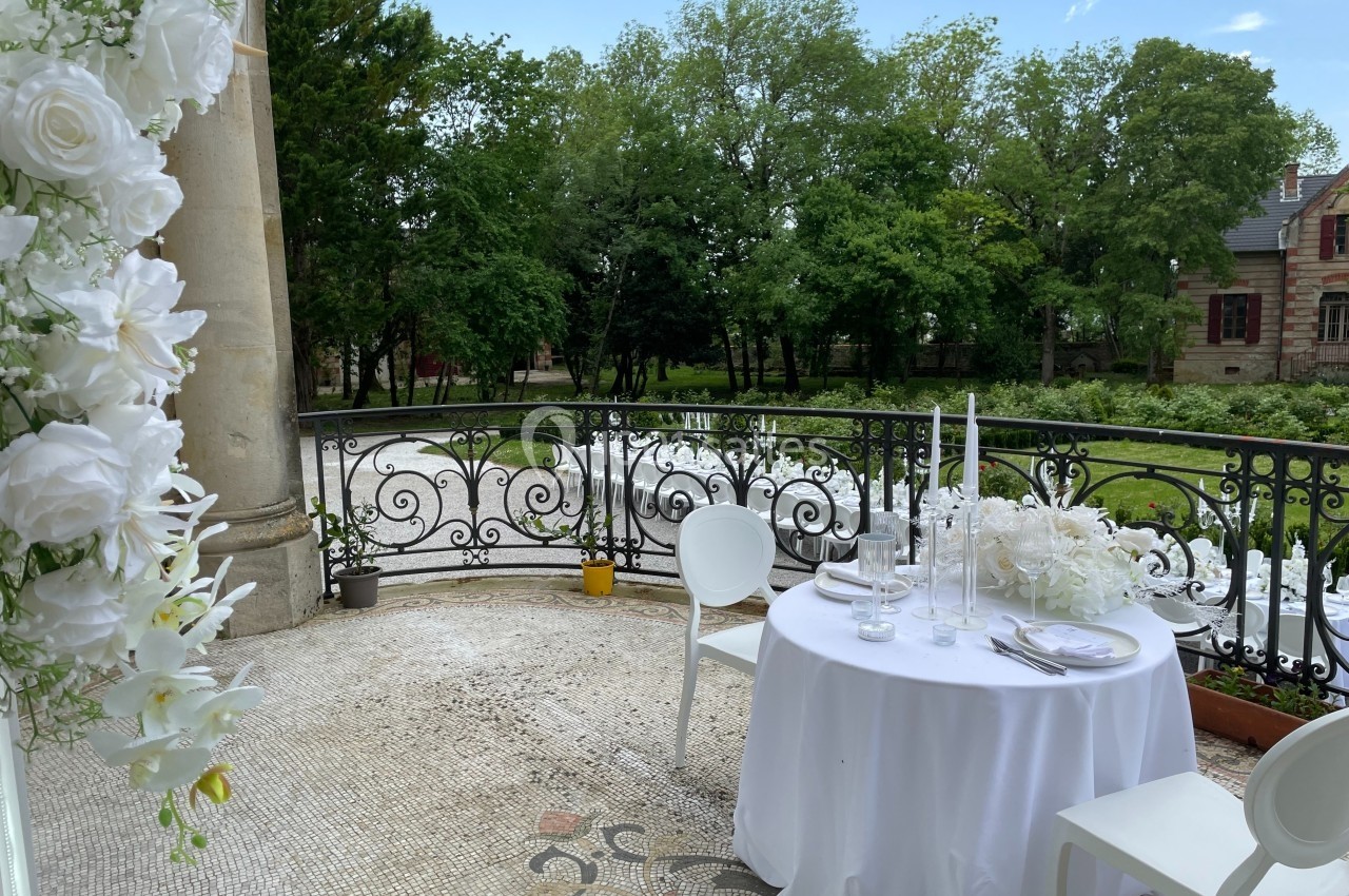 Table dressée avec nappes blanches et chandeliers sur une terrasse donnant sur un jardin verdoyant.