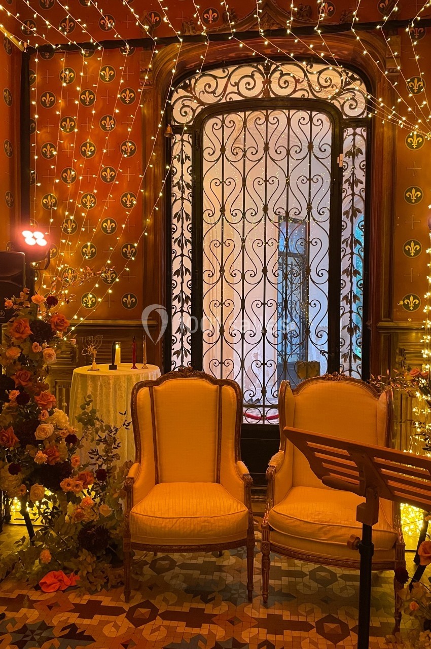 Deux fauteuils jaunes dans une pièce décorée de fleurs, guirlandes lumineuses et motifs dorés sur les murs.
