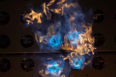 Colonnes de panneaux métalliques perforés émettant des flammes dans un environnement extérieur nocturne.
