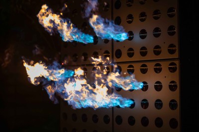 Colonnes de panneaux métalliques perforés émettant des flammes dans un environnement extérieur nocturne.
