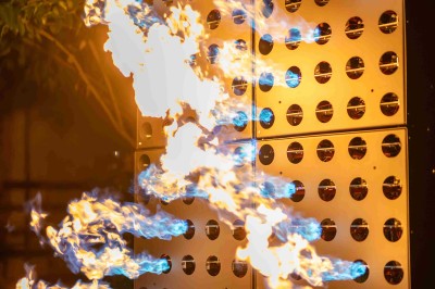 Colonnes de panneaux métalliques perforés émettant des flammes dans un environnement extérieur nocturne.
