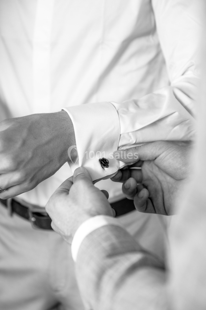 Une personne ajuste le bouton de manchette d'une chemise blanche portée par une autre personne.