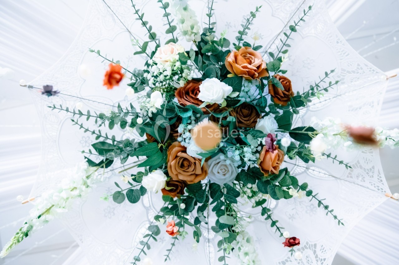 Vue de dessus d'un bouquet floral composé de roses blanches et orangées entourées de feuillage vert.