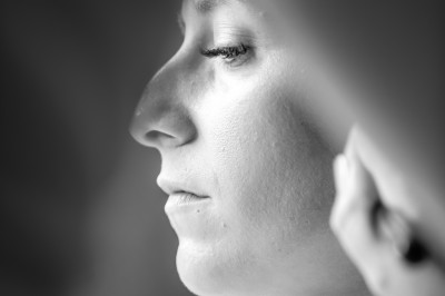 Femme de profil se faisant maquiller les lèvres avec un pinceau dans un cadre lumineux.