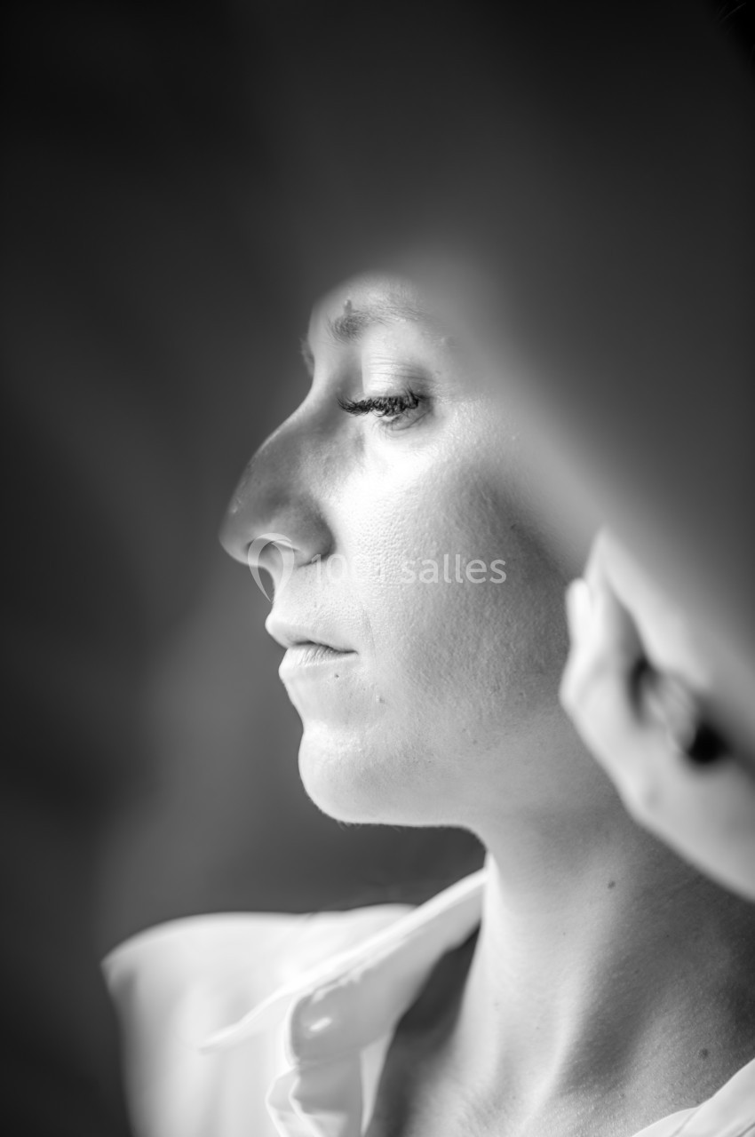 Femme de profil en noir et blanc, éclairée par une lumière douce, les yeux fermés dans un moment de calme.