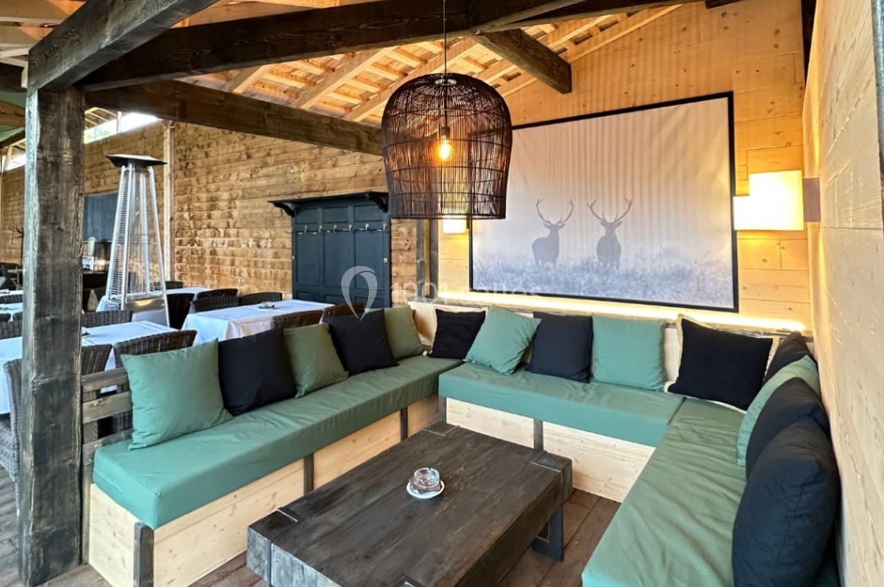 Espace salon en bois avec banquettes vertes, table basse et décoration murale représentant des cerfs.