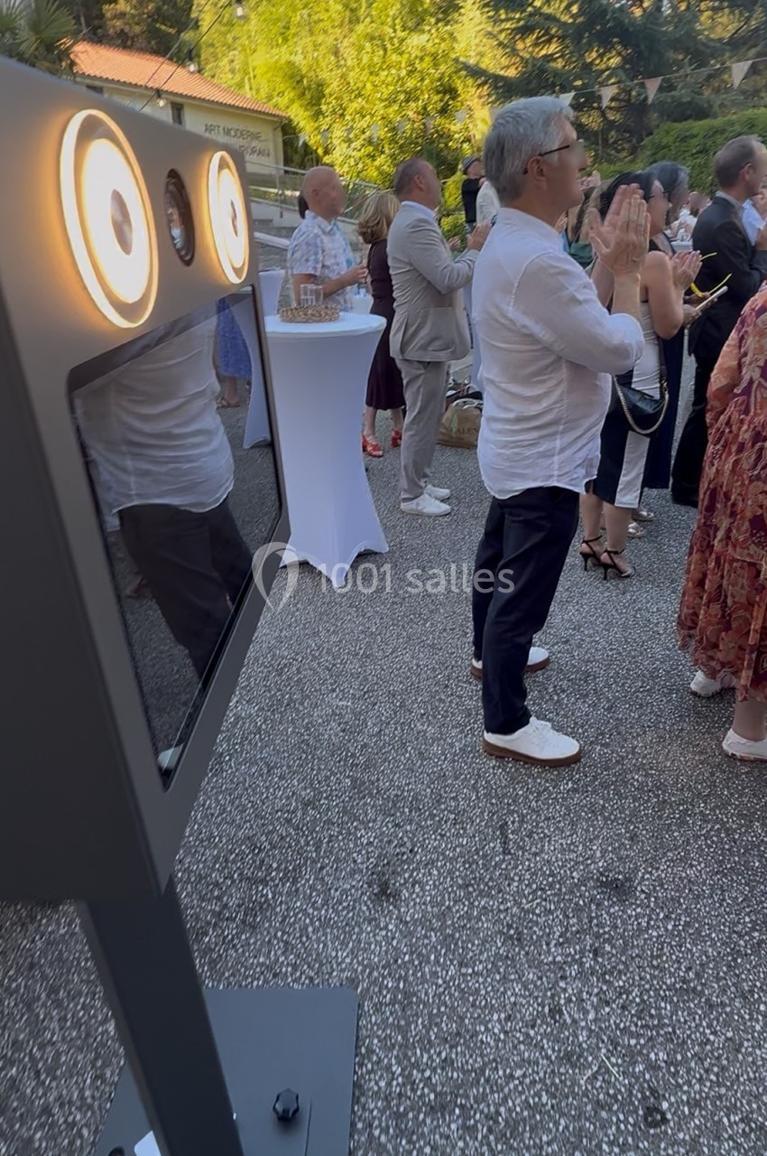 Personnes debout en extérieur lors d'un événement, près d'une borne photo équipée de lumières circulaires.