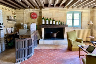 Miniature Location salle Arveyres (Gironde) - Château la Capelle #30 Bouteilles de vin alignées sur des supports métalliques dans une cave aux murs en pierre.