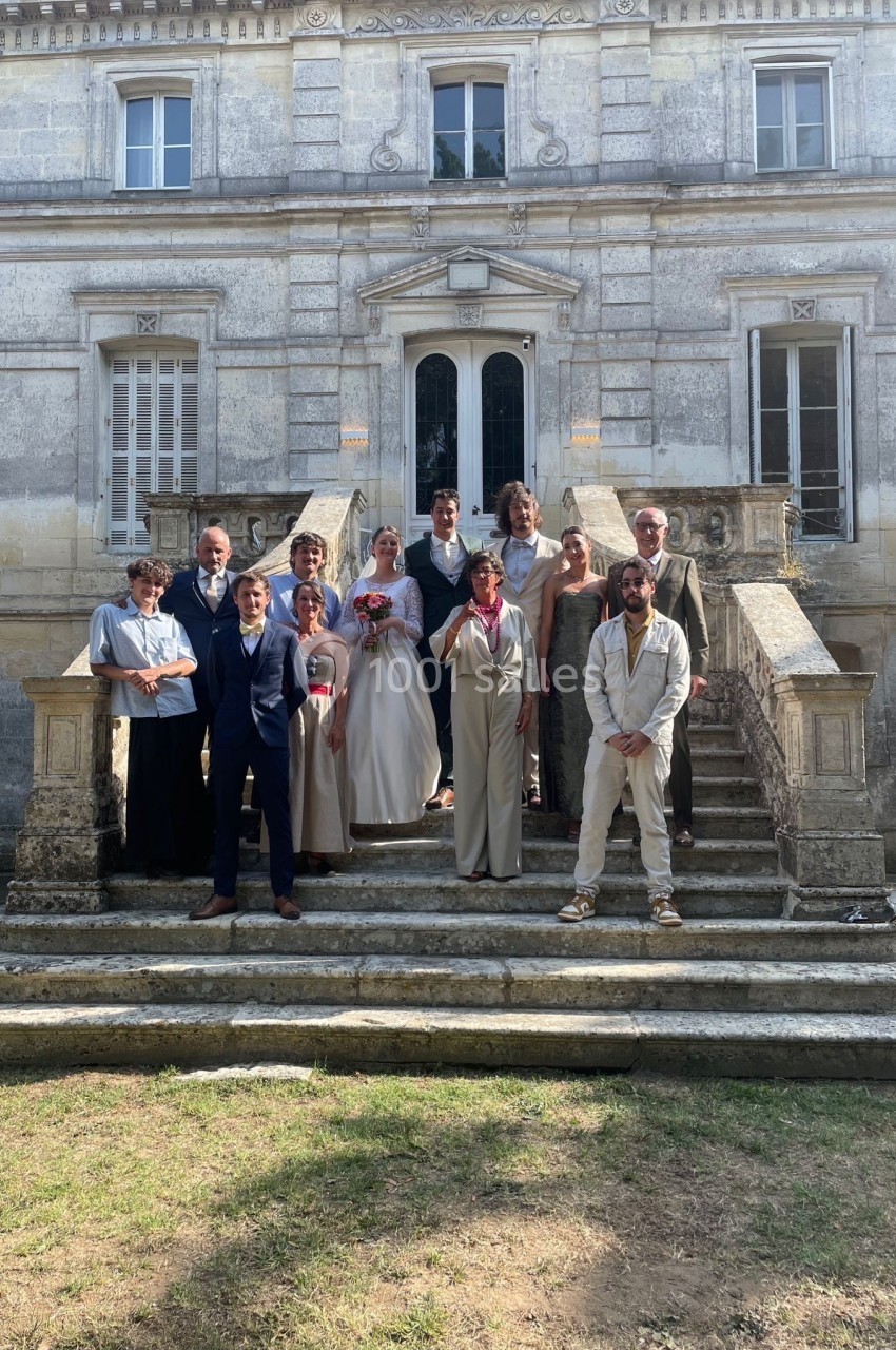 Un groupe de personnes posant sur les marches d'un bâtiment ancien en pierre, par une journée ensoleillée.