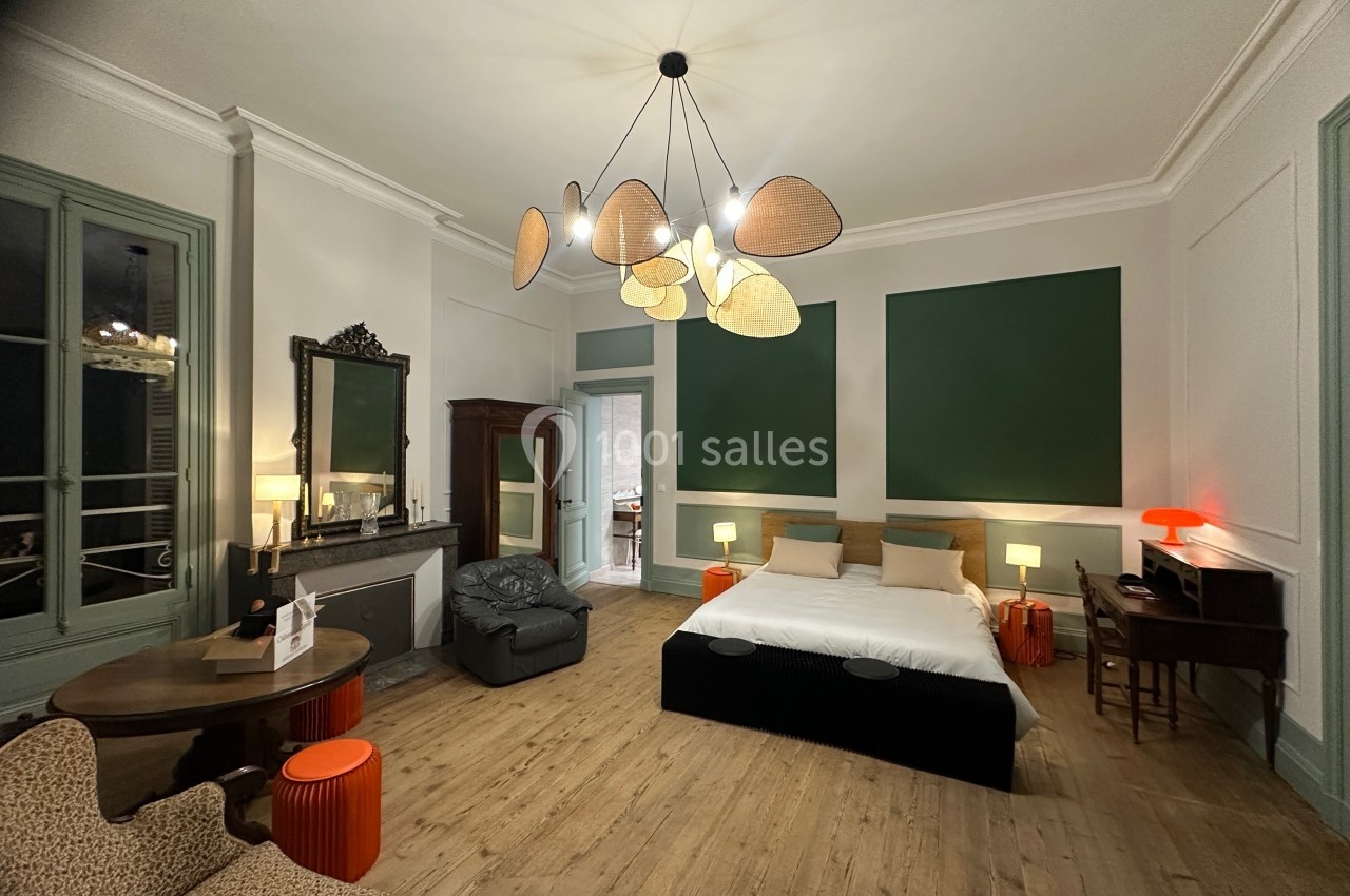 Chambre spacieuse avec lit double, mobilier en bois, éclairage moderne et murs décorés de panneaux verts.