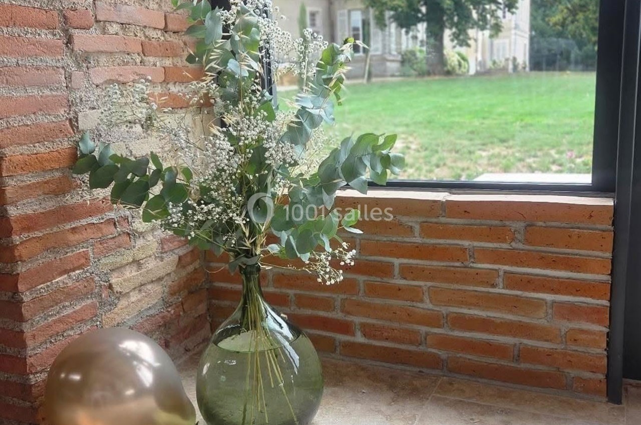 Vase en verre transparent contenant des branches d'eucalyptus et de gypsophile, posé près d'une fenêtre avec vue sur un…