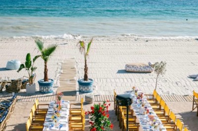 Chaises en rotin entourées de pampas et de décorations jaunes, sous un parasol blanc dans un cadre lumineux.