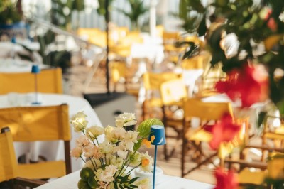 Chaises en rotin entourées de pampas et de décorations jaunes, sous un parasol blanc dans un cadre lumineux.