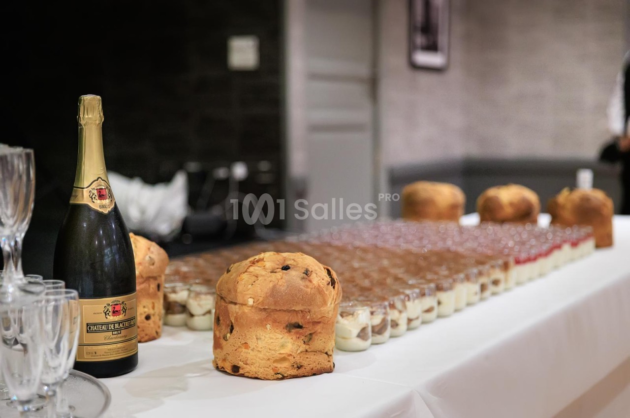 Table de présentation avec bouteille de champagne, verres, panettone et petits fours alignés.