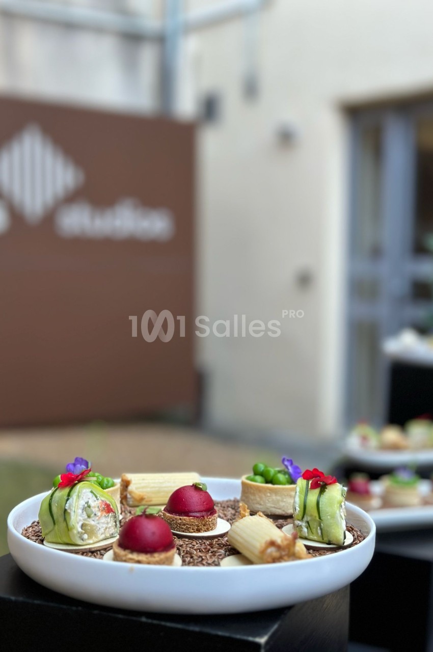 Assiette de dégustation avec amuse-bouches gastronomiques devant bâtiments de pierre.