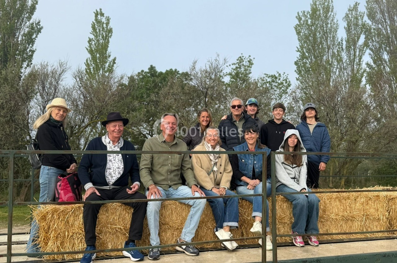 Un groupe de personnes assises sur des bottes de paille, en extérieur, entouré d'arbres.