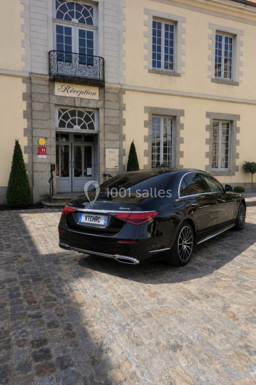 Voiture noire garée devant l'entrée d'un bâtiment élégant avec une enseigne ’Réception’.