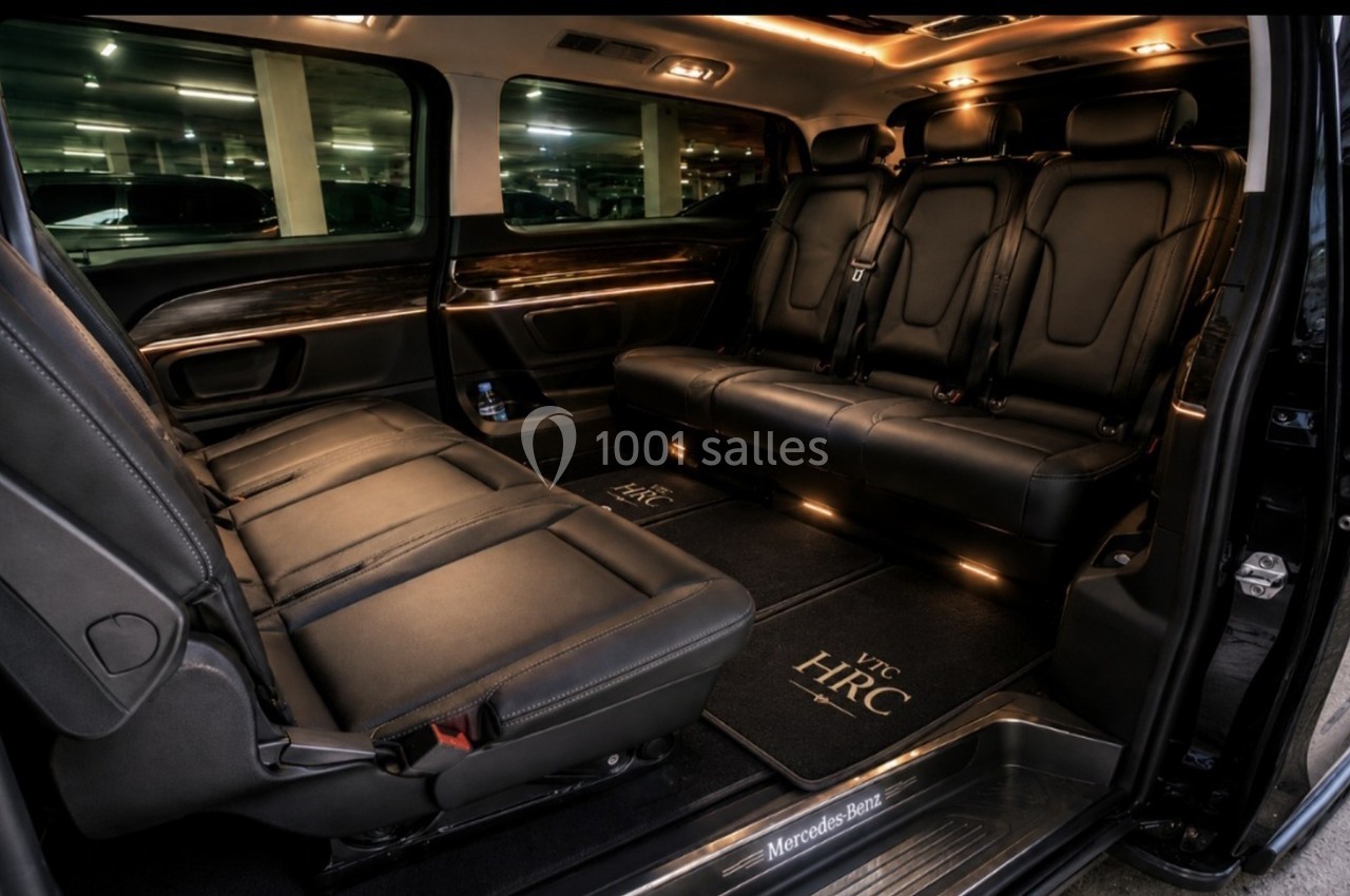 Intérieur d'un van haut de gamme avec sièges en cuir noir, éclairage d'ambiance et tapis personnalisés.