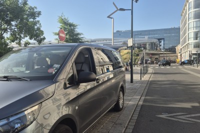 Deux véhicules Mercedes noirs stationnés sur un sol pavé devant un bâtiment en pierre sous un ciel nuageux.