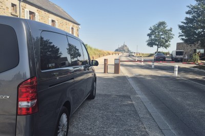 Deux véhicules Mercedes noirs stationnés sur un sol pavé devant un bâtiment en pierre sous un ciel nuageux.
