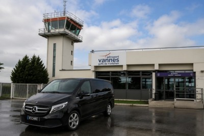 Deux véhicules Mercedes noirs stationnés sur un sol pavé devant un bâtiment en pierre sous un ciel nuageux.