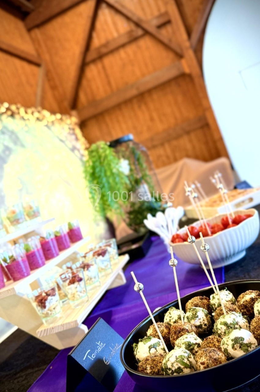 Plateau de boules apéritives aux herbes, accompagné de verrines et d'autres mets sur une table décorée.