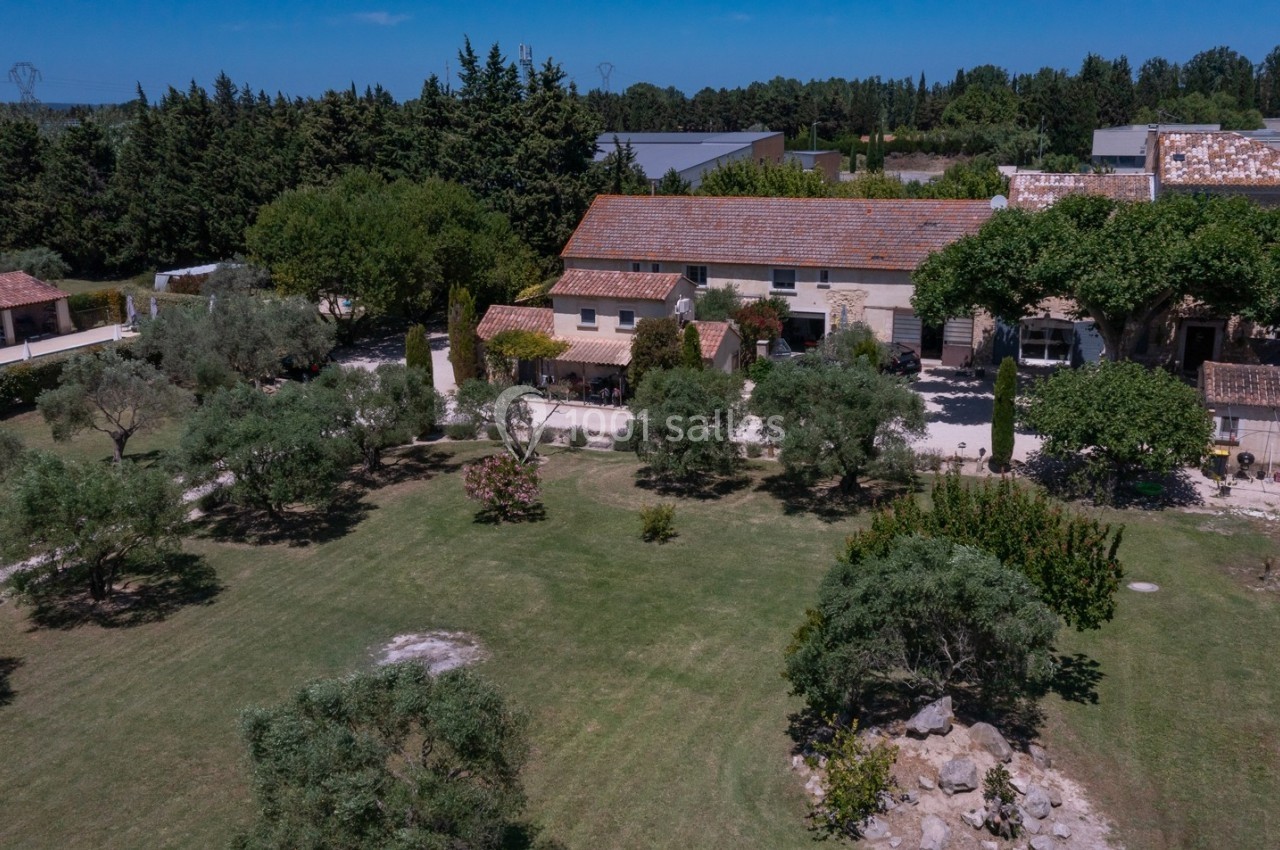 Vue aérienne d'une grande maison en pierre entourée d'arbres, avec un jardin spacieux et des bâtiments annexes.