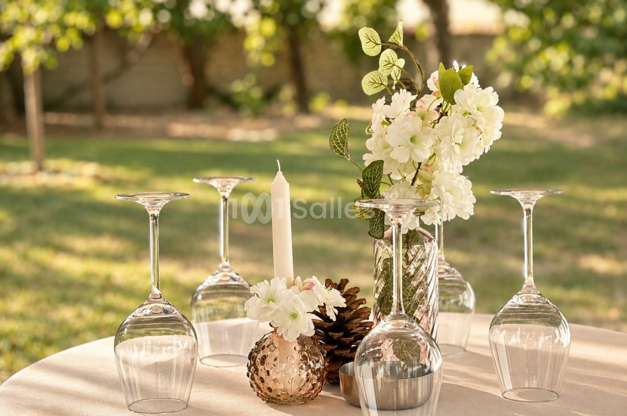 Composition florale avec fleurs blanches en vase de cristal - candélabre et bougie sur table en terrasse.