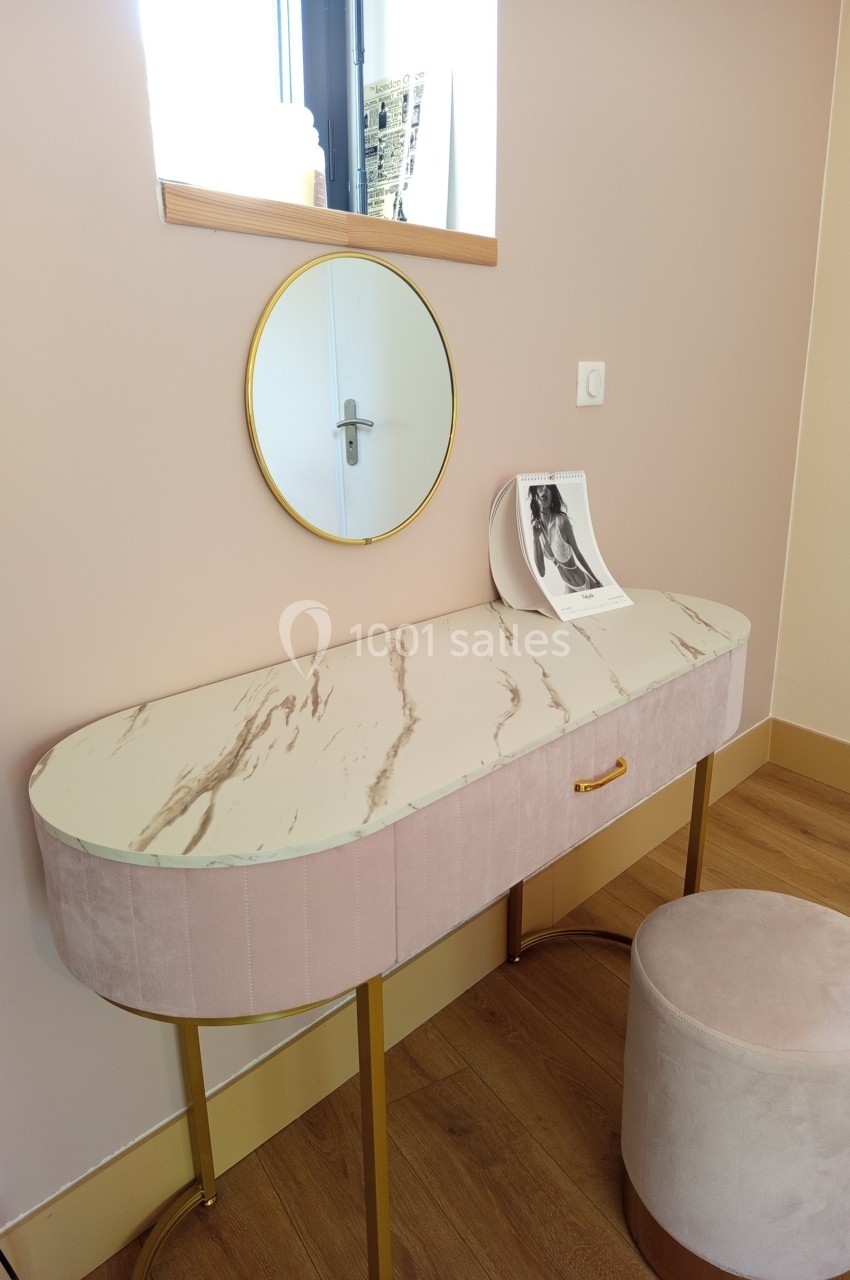 Coiffeuse avec plateau effet marbre, miroir rond doré, tabouret assorti et photo posée sur le meuble.