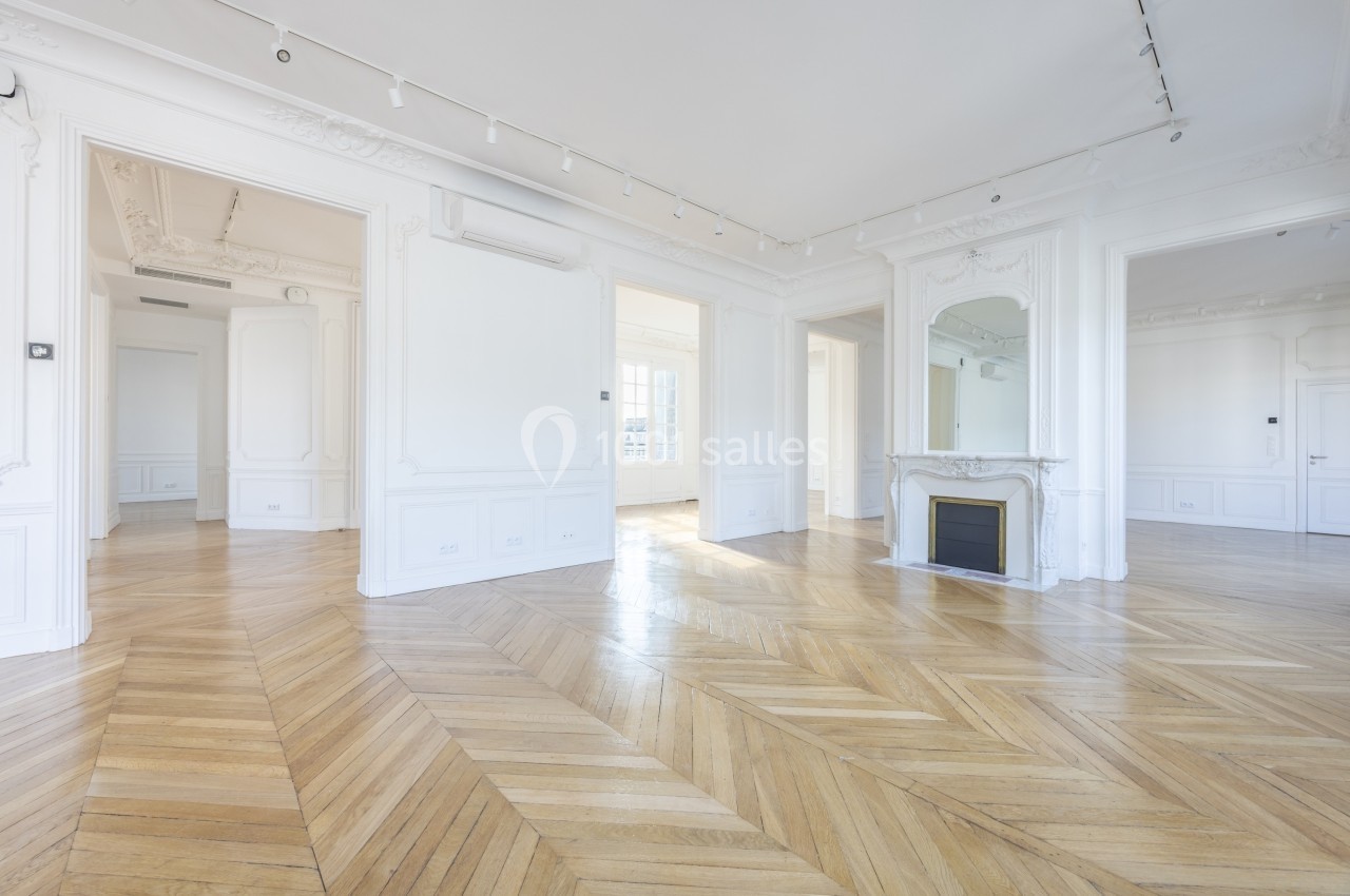 Appartement lumineux avec parquet en chevrons, moulures au plafond, cheminée décorative et grandes ouvertures.