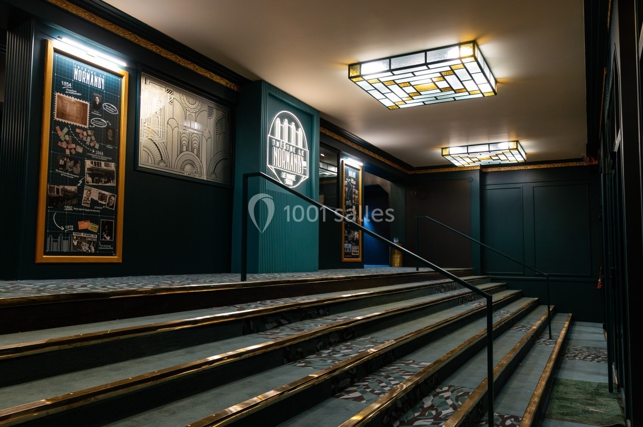 Escalier intérieur avec rampe, éclairé par des plafonniers en vitrail, entouré de panneaux décoratifs muraux.