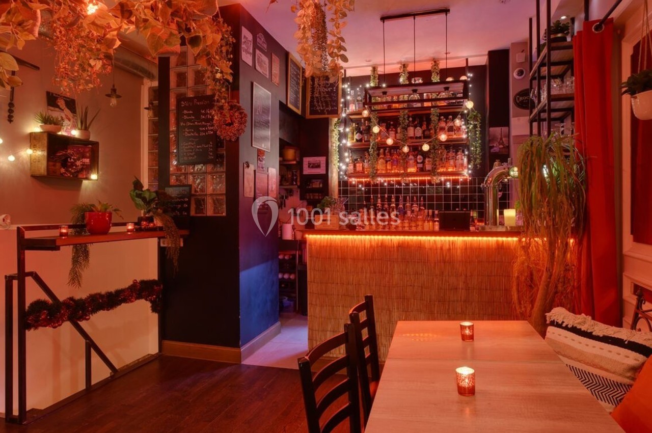 Intérieur d'un bar chaleureux avec éclairage tamisé, décor végétal et comptoir illuminé.