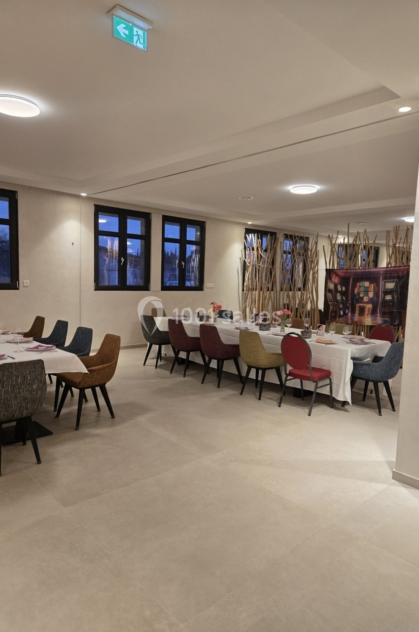 Salle à manger spacieuse avec tables dressées, chaises colorées et décorations murales en bois.